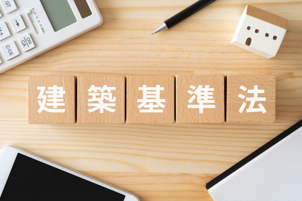 建築基準法と書かれたブロック、スマホ、電卓、ノート、家の置物